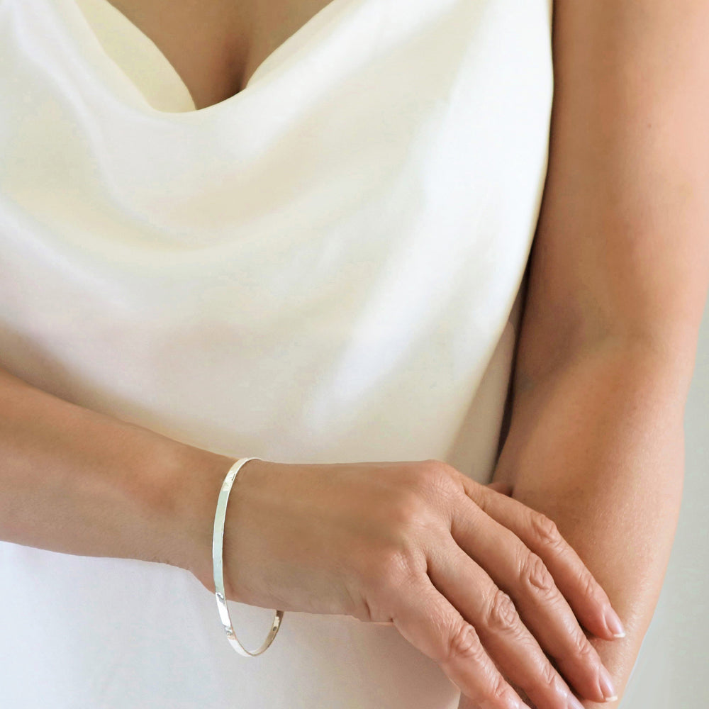 A woman wearing a slender silver bangle with a hammered finish