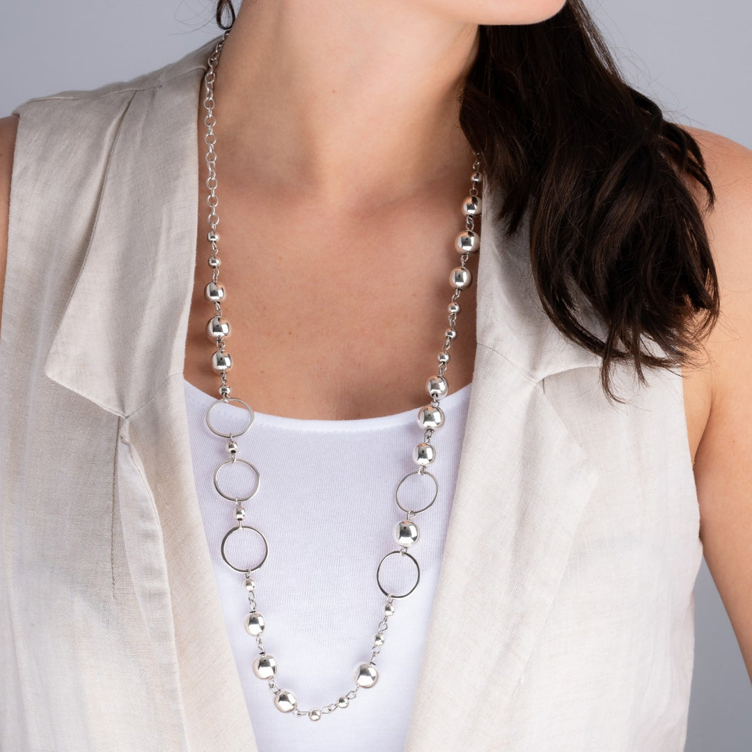 Woman wearing a long 925 sterling silver fancy link chain necklace, styled with casual clothing.