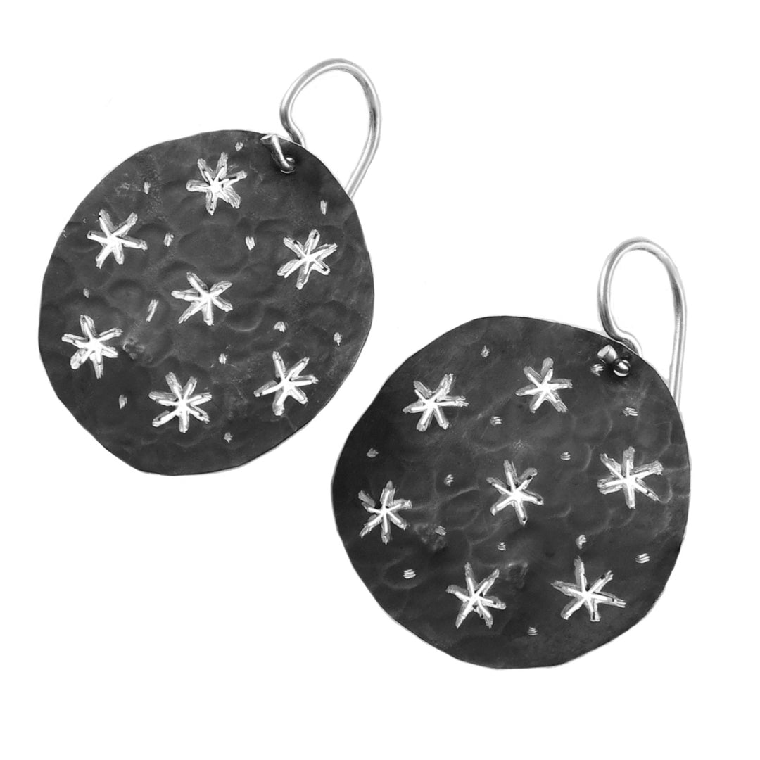 Antiqued silver earrings with star patterns on a white background