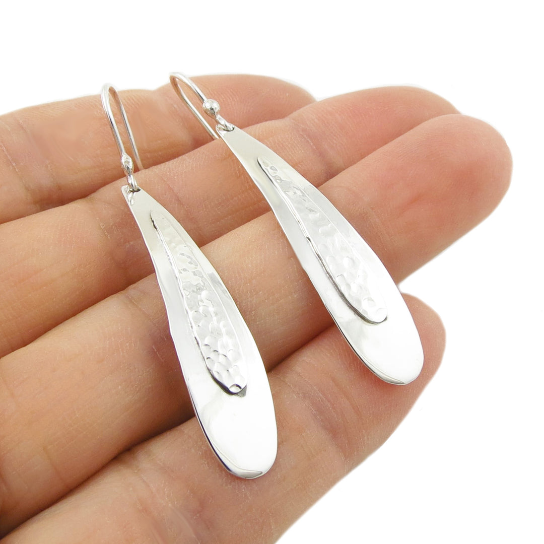 Long curved silver drop earrings featuring a hammered inlay