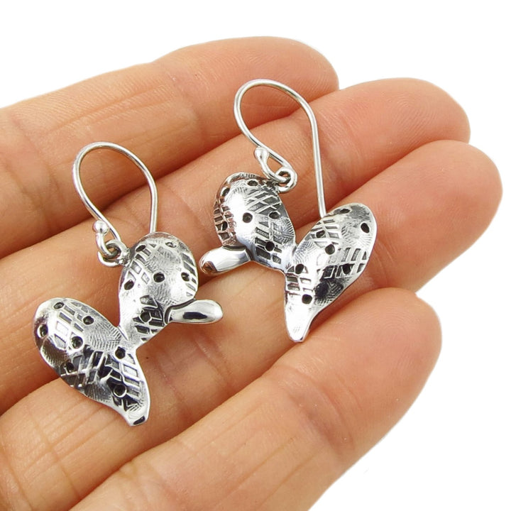 Sterling silver cactus earrings held in a person's hand on a white background.