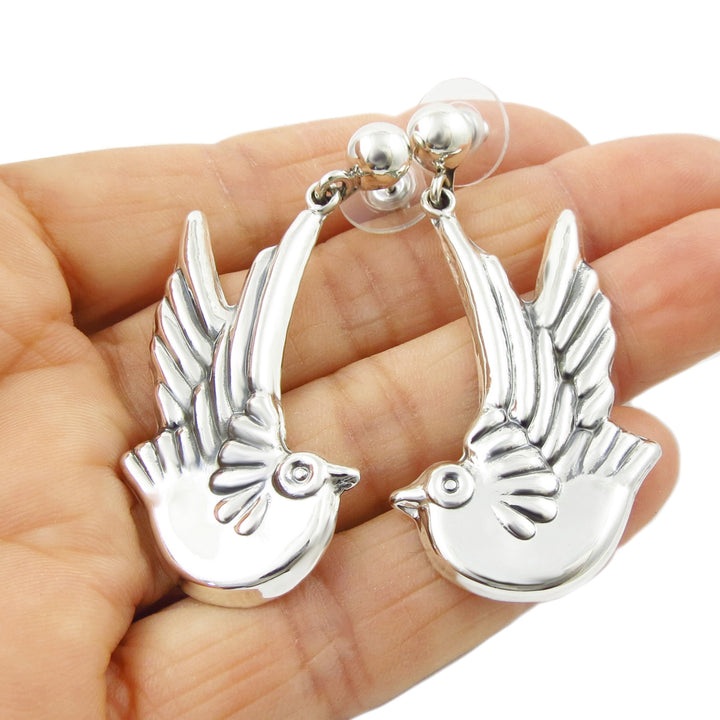 Maria Belen Nilson lovebird earrings in silver held in a person's hand on a white background