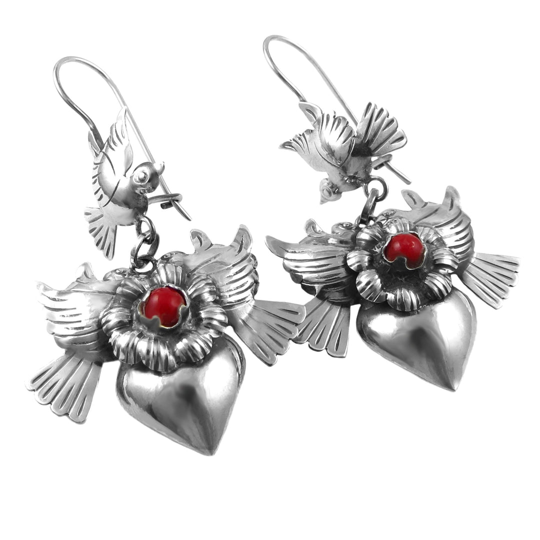 A pair of silver earrings featuring a design of doves, hearts, and flowers with bright red centers.