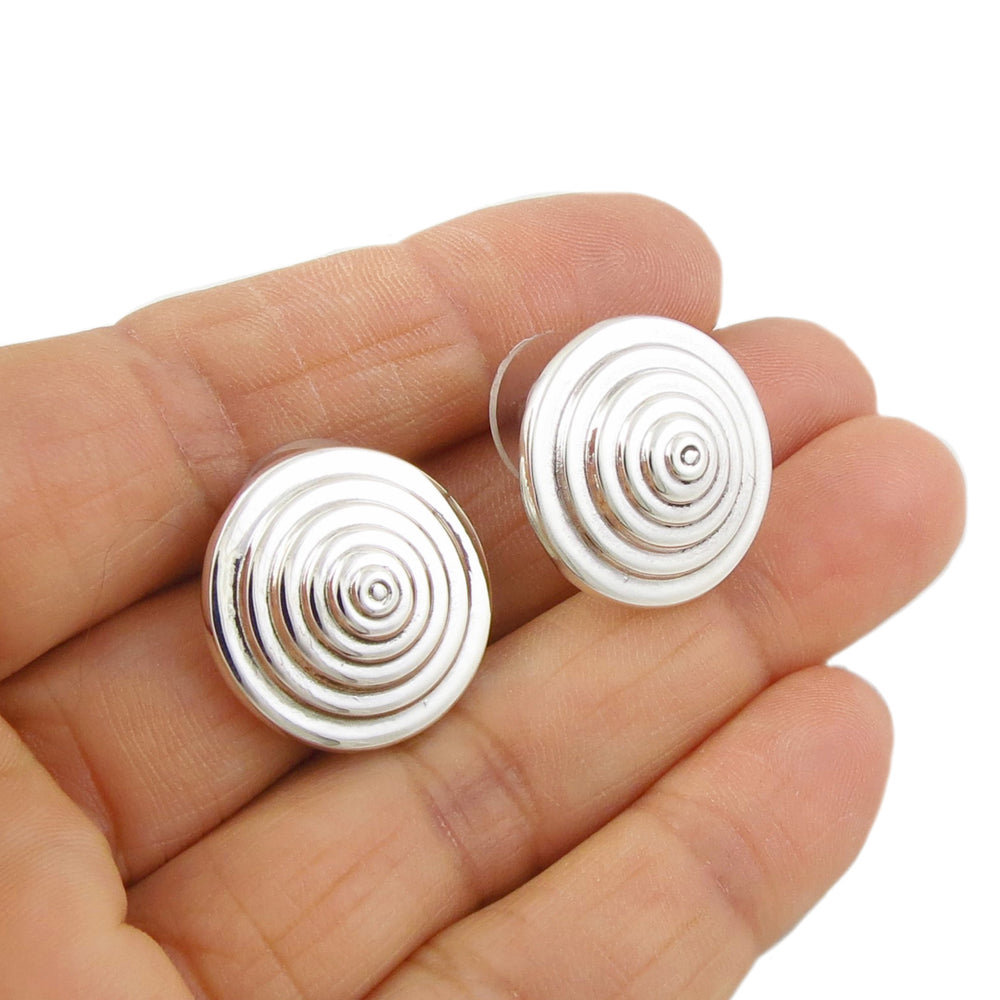 Sculpted sterling silver circle stud earring held in a person's hand.