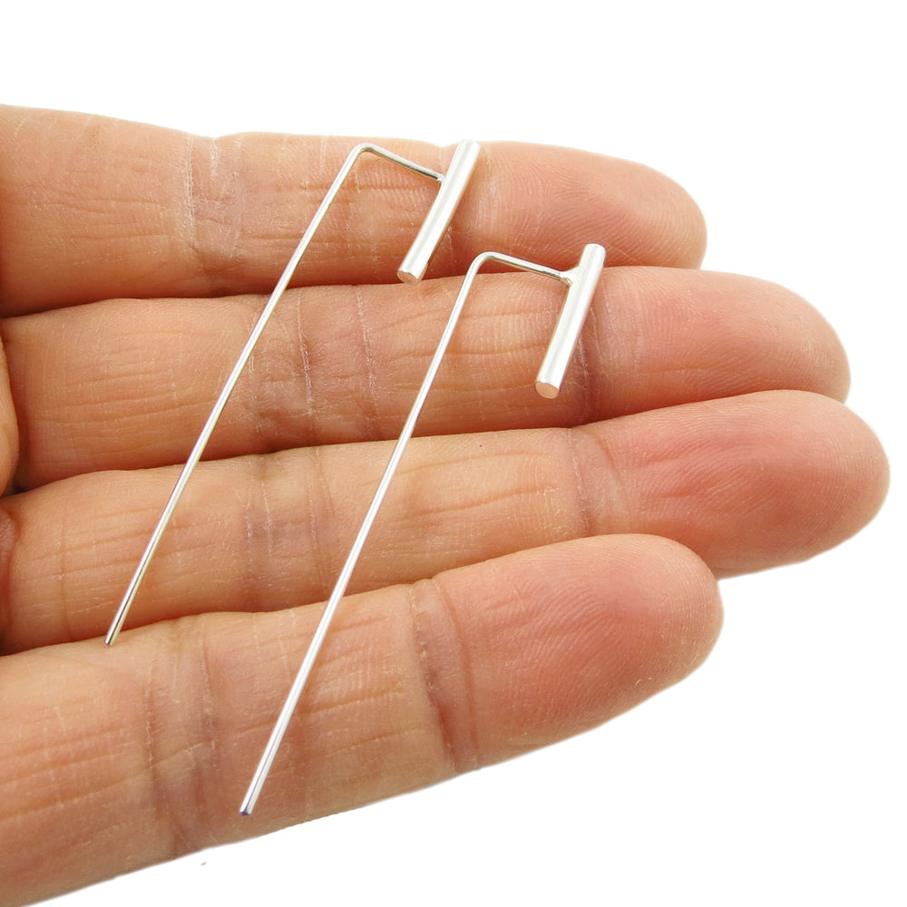 Long sterling silver threader earrings held in a person's hand.