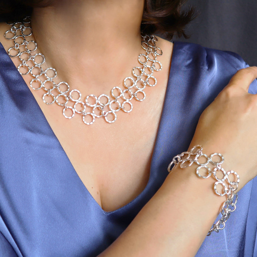 A person wearing a sterling silver wide circle link necklace and matching bracelet.