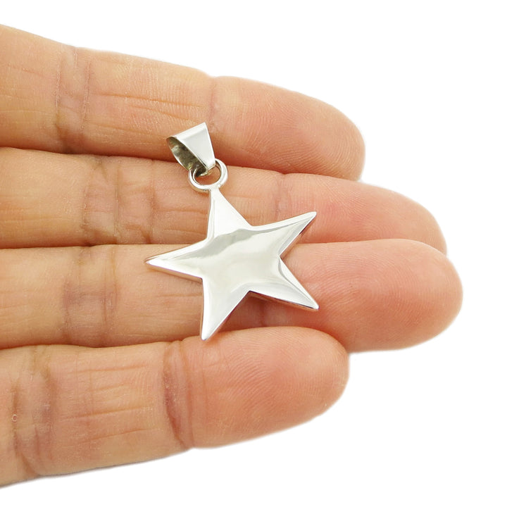 A hand holding a silver pendant necklace with a star shape.