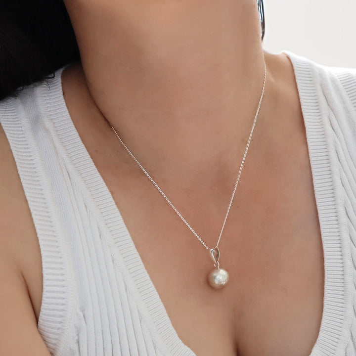 Sterling silver ball bead pendant necklace with a matt finish on a person wearing a white sweater