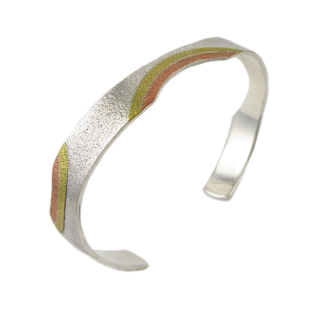 A sterling silver and copper tri metal bracelet with a textured finish.