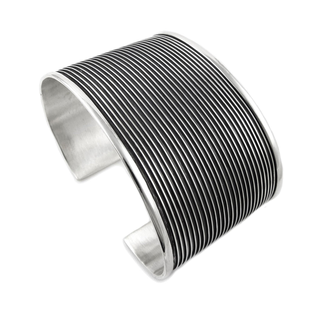 A silver cuff bracelet with hand-drawn lines design, showcasing a modernist style.