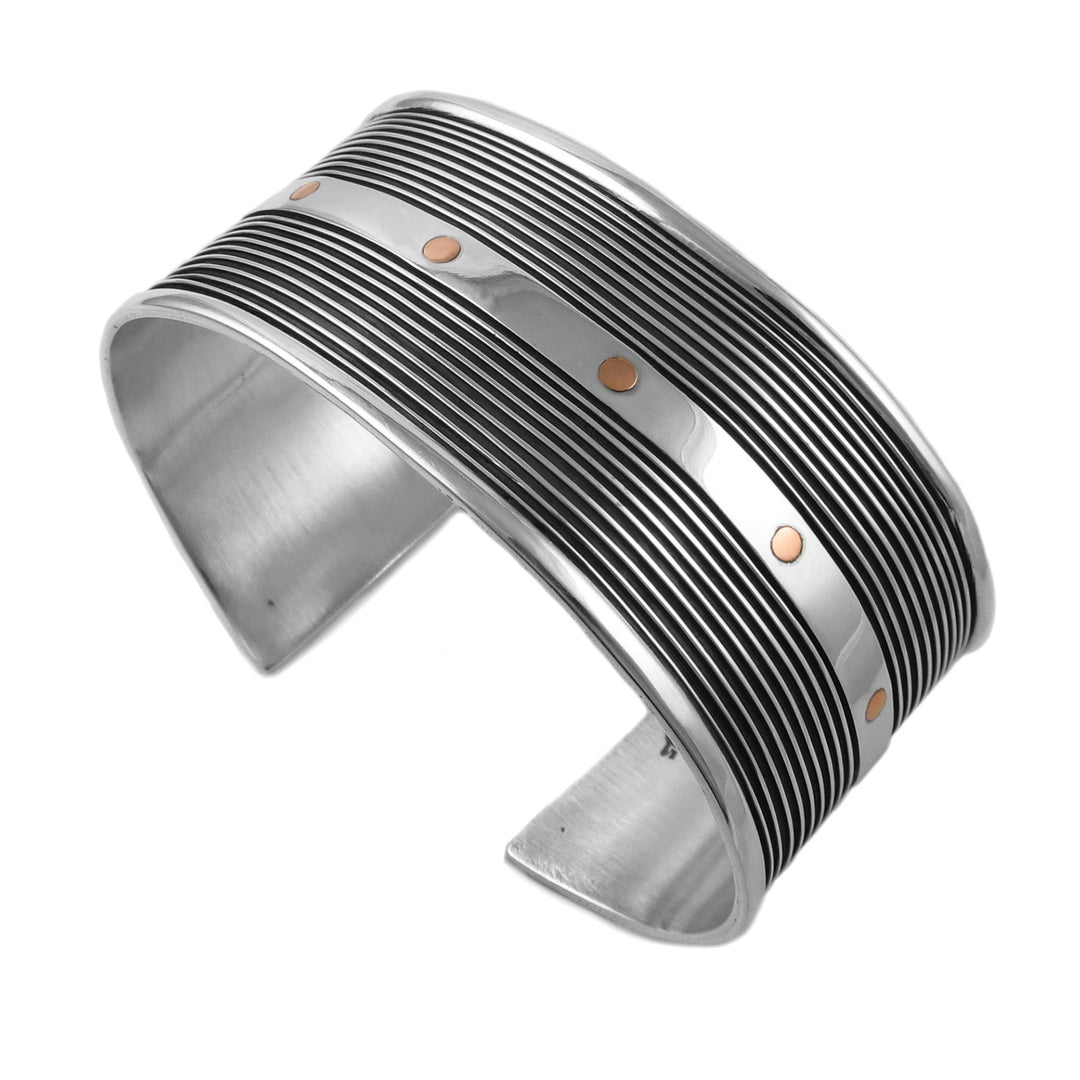 A sterling silver cuff bracelet with copper accents and engraved grooves, designed by Maria Belen Nilson.