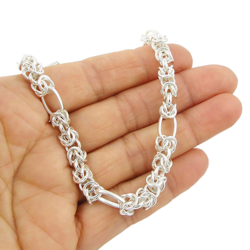 Sterling silver byzantine chain bracelet held in a person's hand.