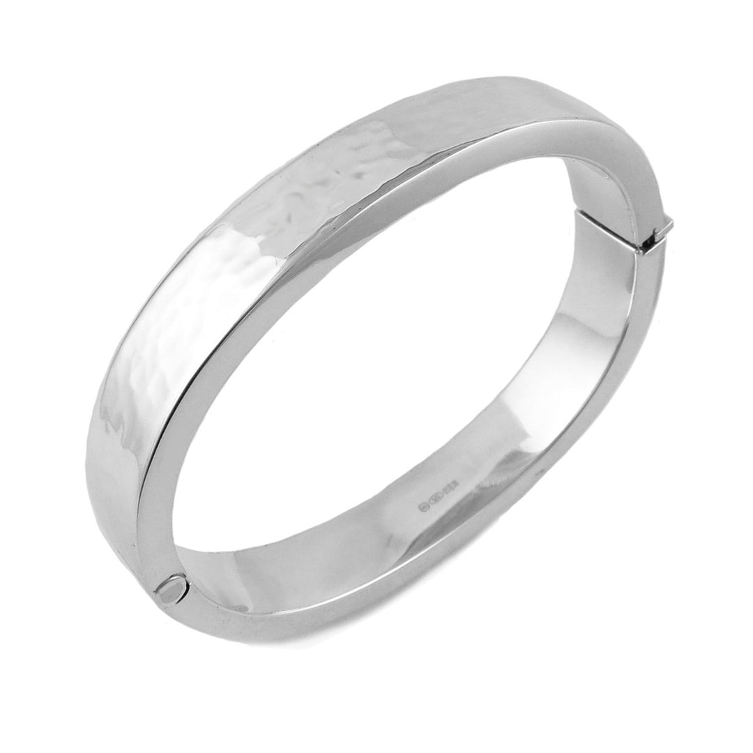 A chunky, hand hammered sterling silver hinged oval bangle bracelet with a polished finish.