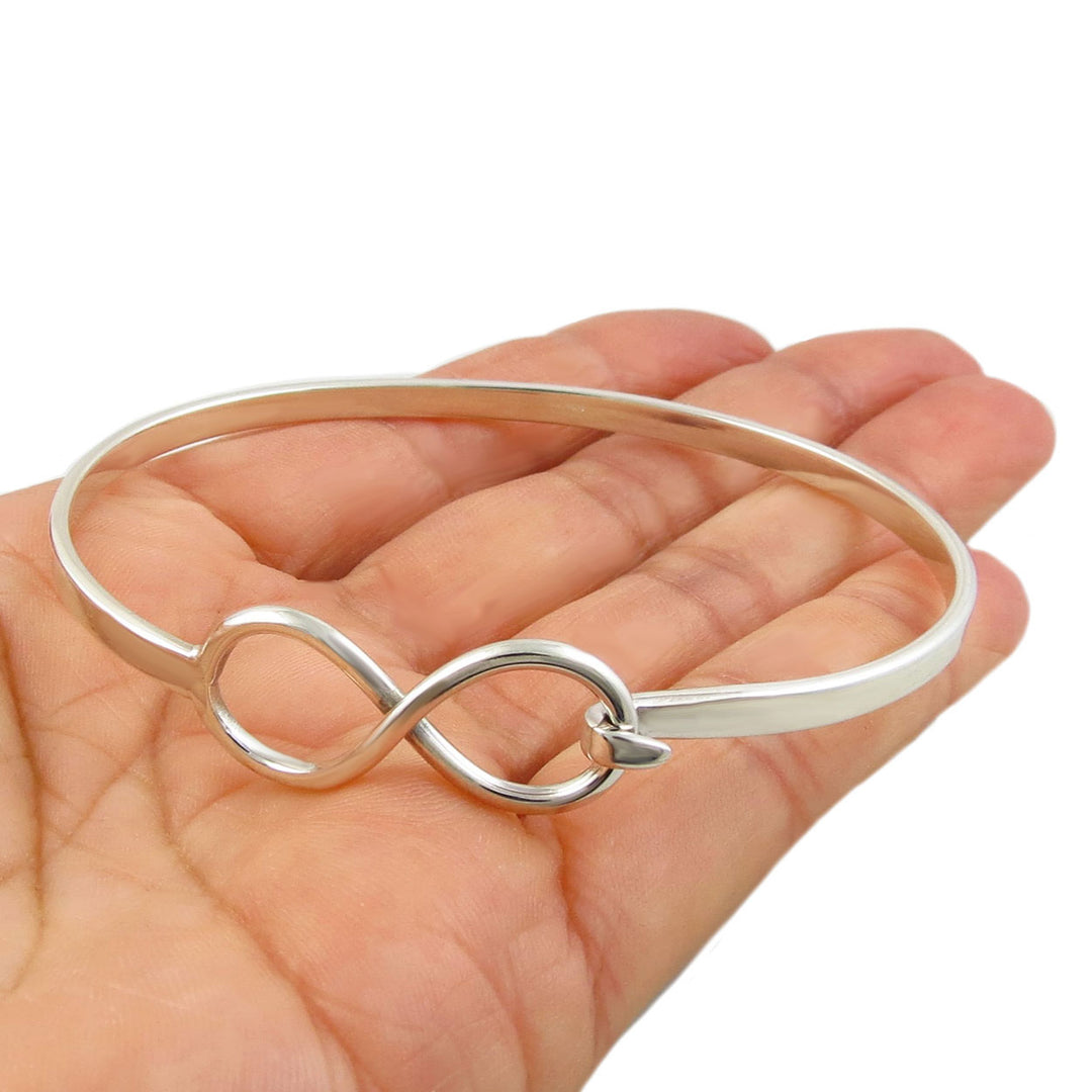 Silver figure of eight infinity bracelet on a hand against a white background
