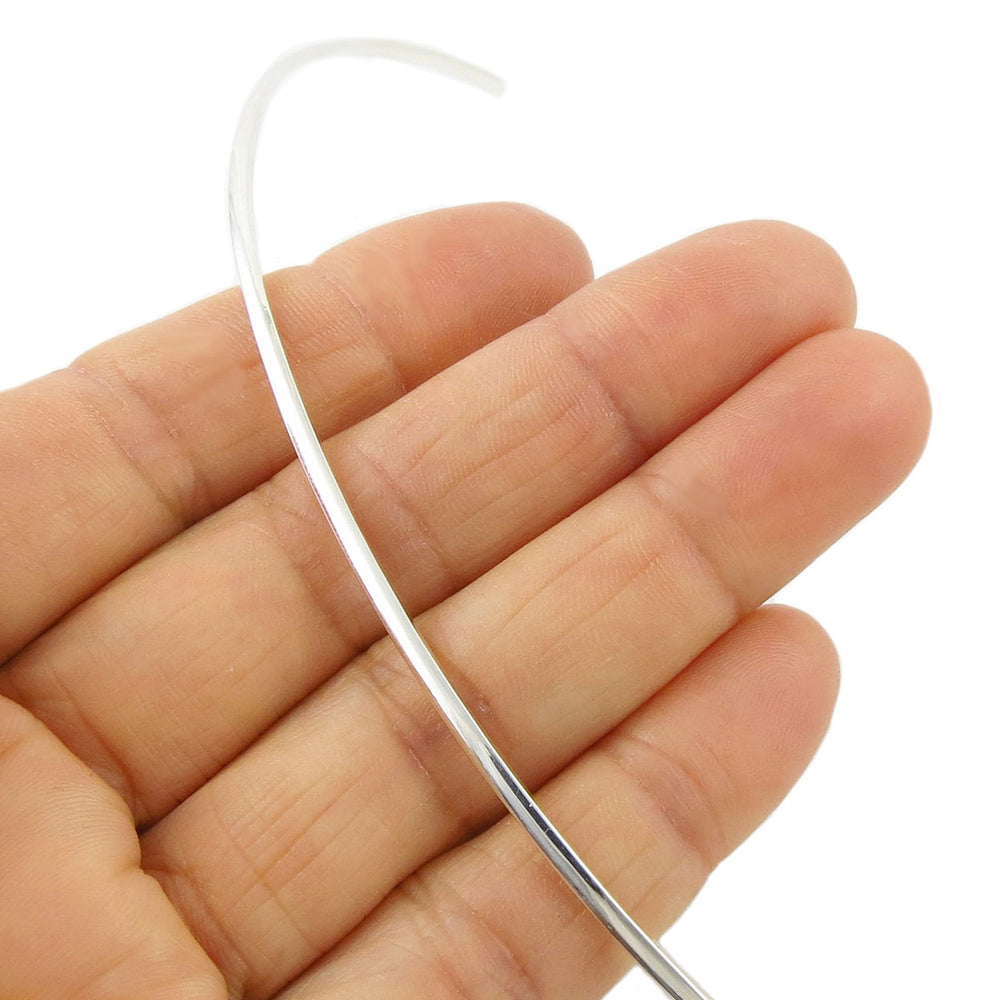 Sterling silver slider choker torque held in a person's hand