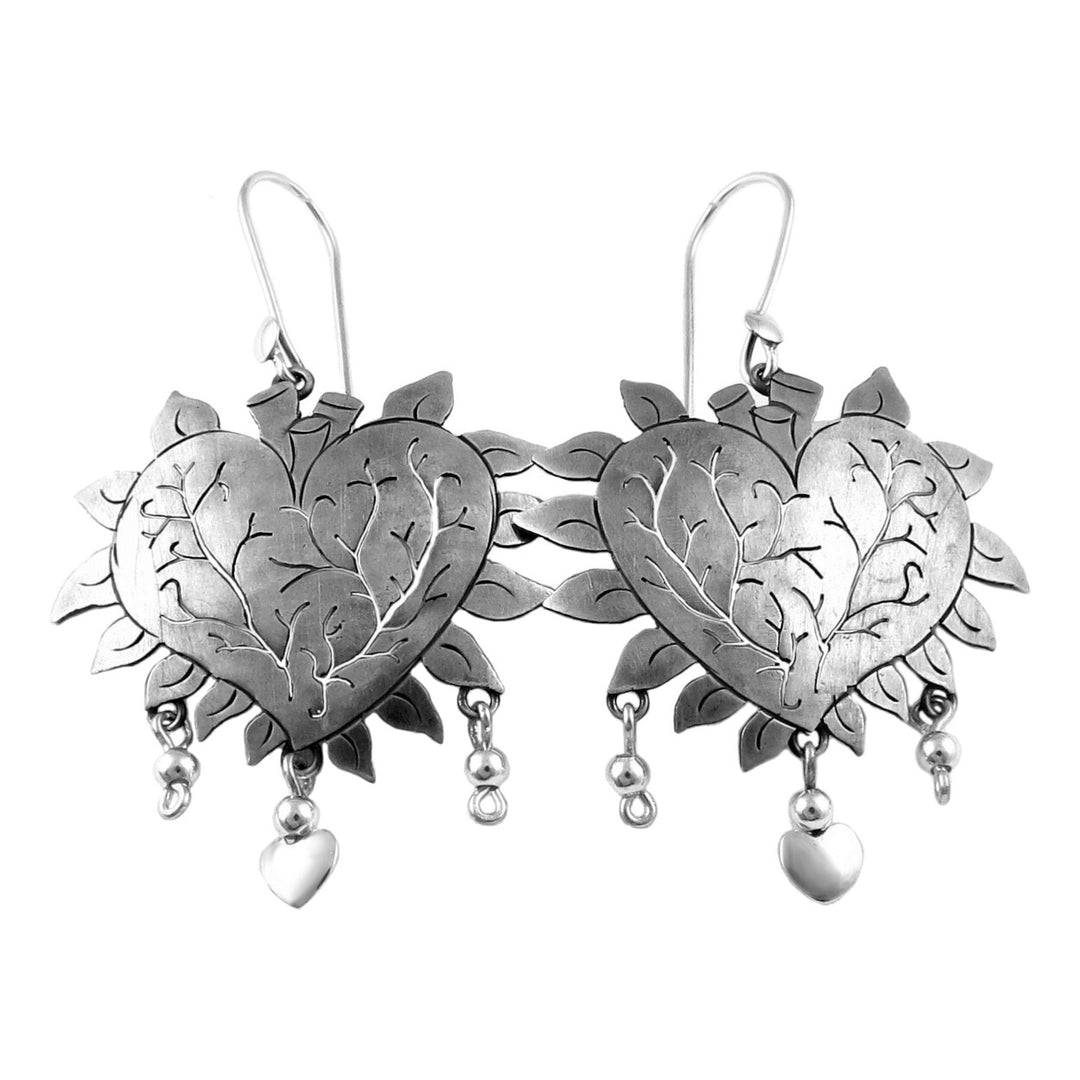 A pair of sterling silver heart-shaped earrings with openwork curling vines design and dangling drops, predominantly silver in color.