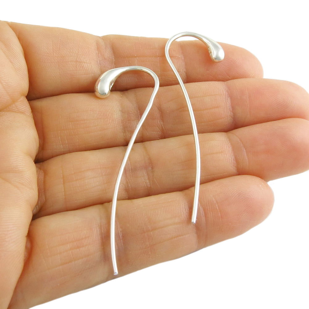 Long pull through sterling silver threader teardrop earrings held in a person's hand.