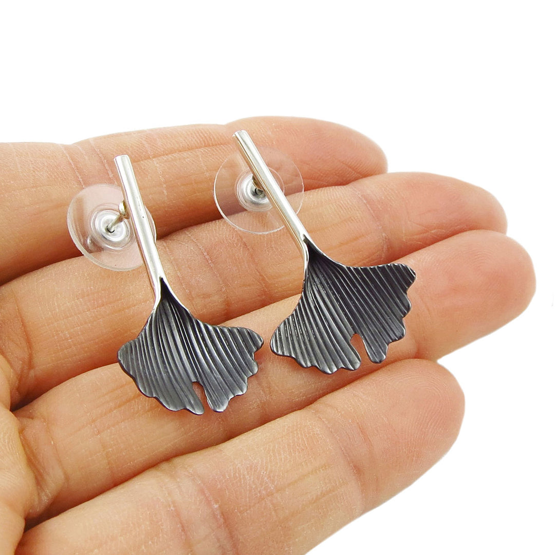 Long gingko leaf earrings in sterling silver held in a person' shand.