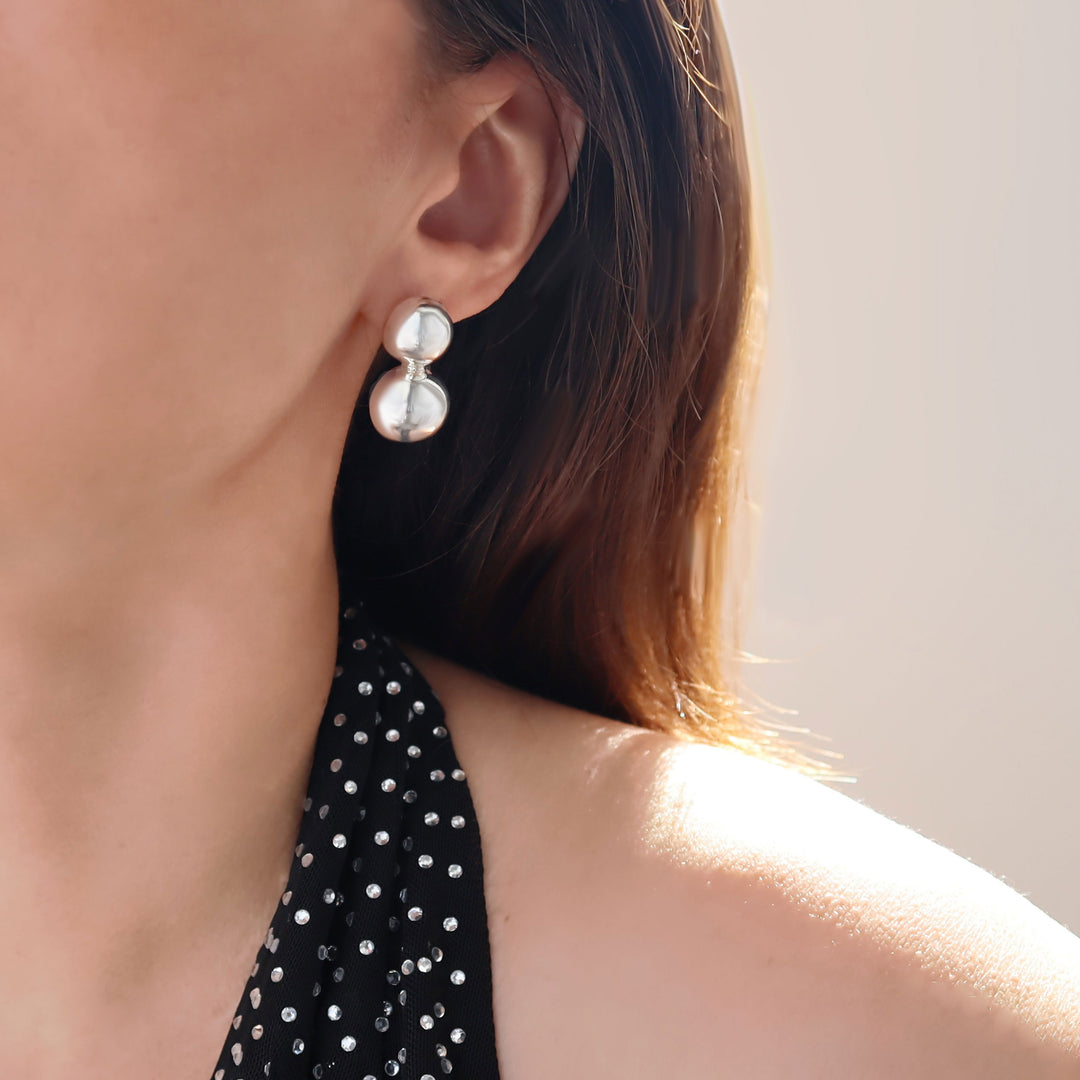 A close-up image of a person wearing a sleeveless top with double ball bead sterling silver earrings.