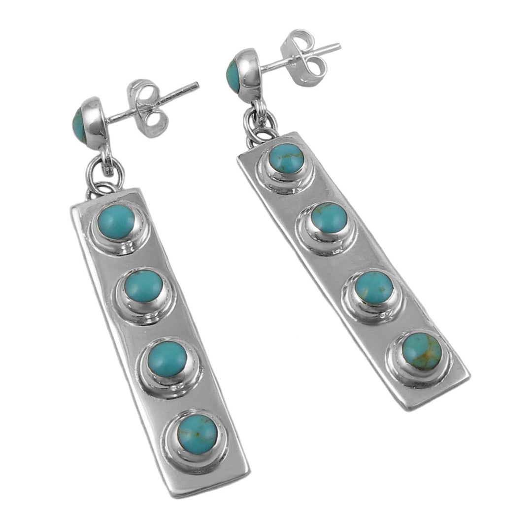 A pair of long rectangular silver earrings with turquoise coloured beads, displayed against a white background.