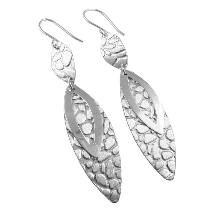 A pair of silver drop earrings with a brushed texture and polished finish, in an asymmetric design.
