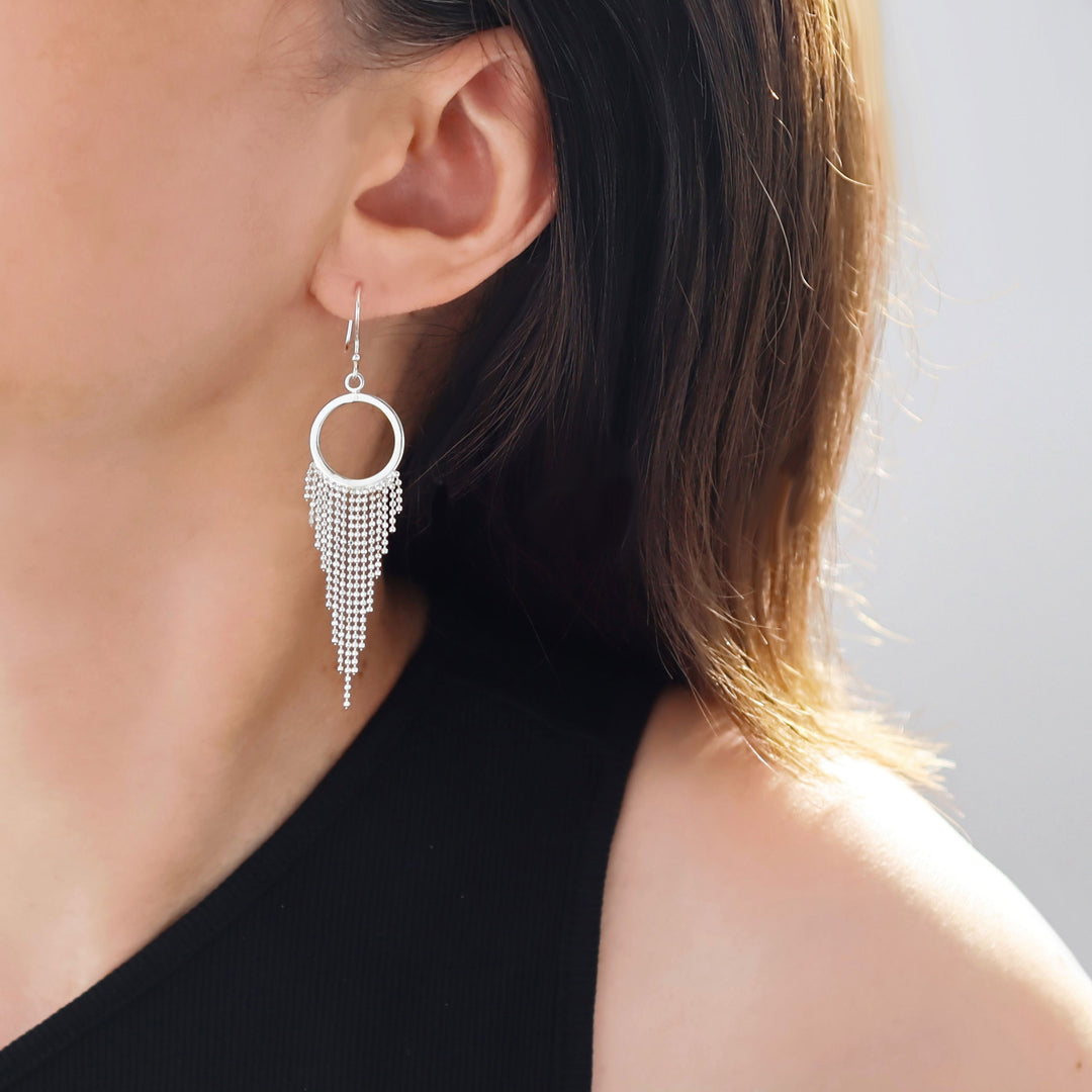 A woman wearing a sterling silver circle earring with a chain fringe.