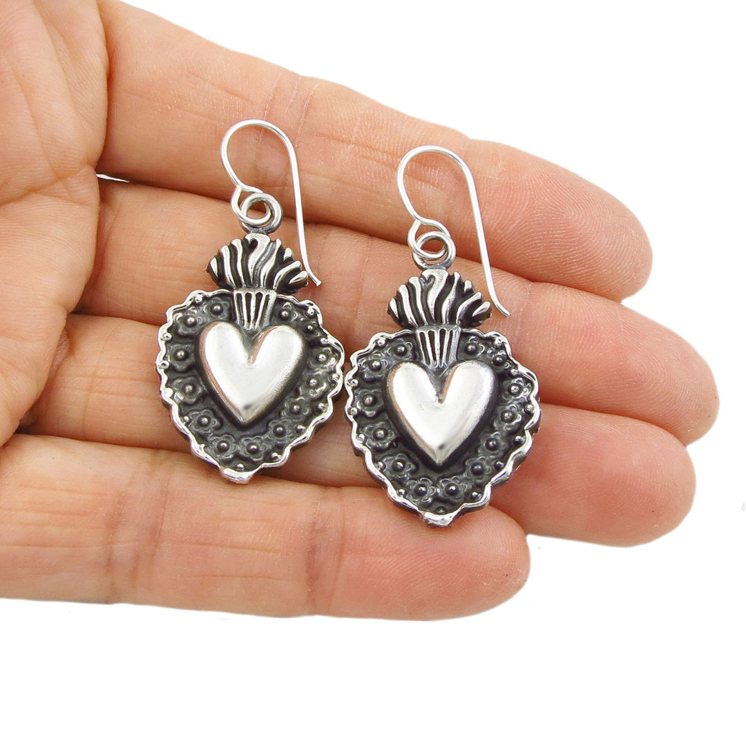 Taxco flaming heart sterling silver earring held in a person's hand