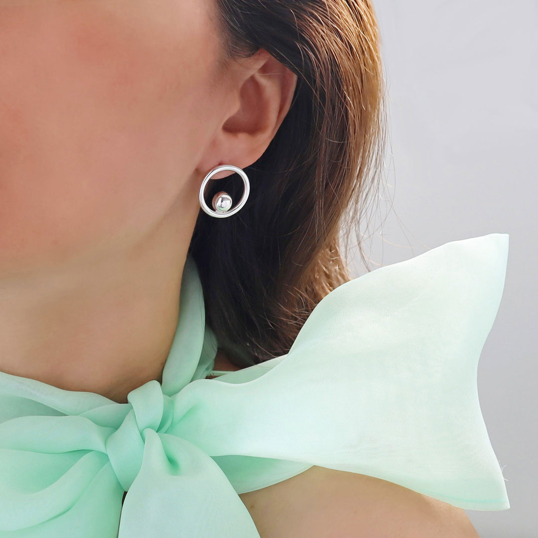 Circle earrings on a person wearing a lime green blouse