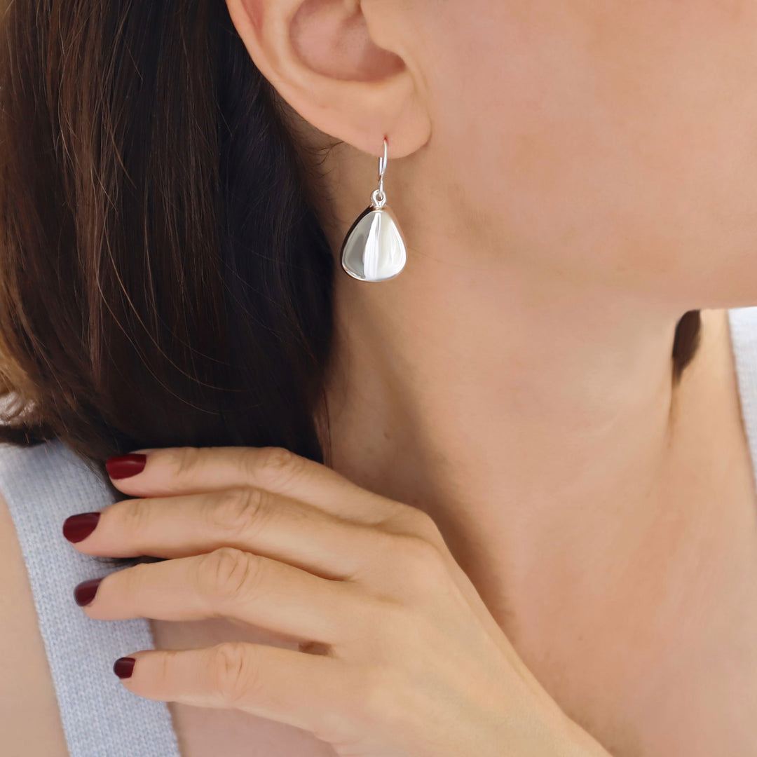 Sterling silver triangle drop earrings worn by a woman
