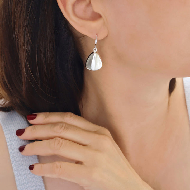 Sterling silver triangle drop earrings worn by a woman
