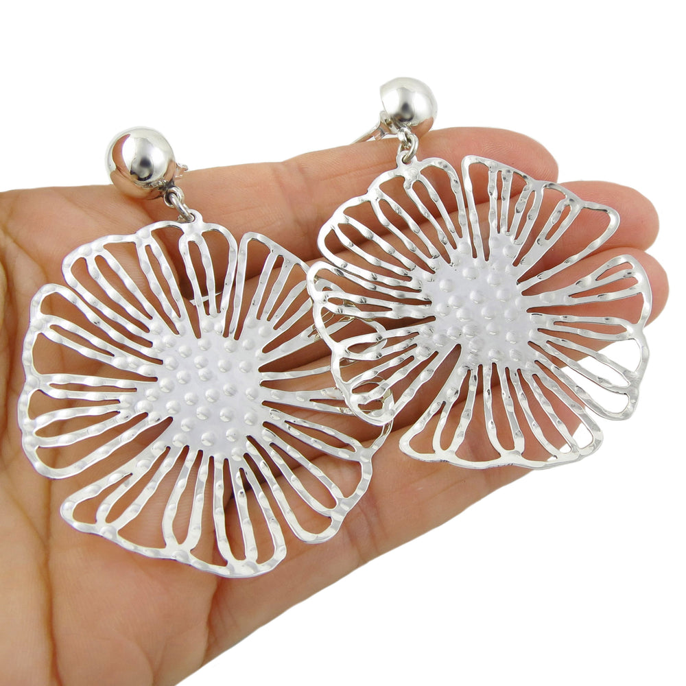 Large sterling silver flower earrings held in a person's hand