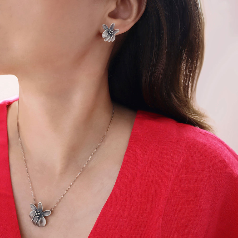 A woman in a pink blouse wearing a moringa flower brushed silver necklace and earrings.