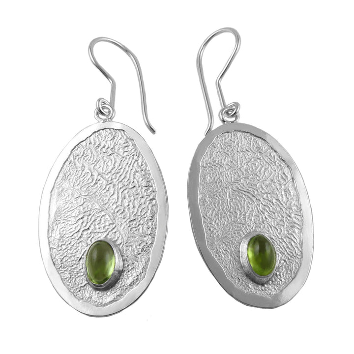 A pair of sterling silver earrings with large oval peridot gemstones and a crumpled silver effect base, featuring sculptured ear hooks.