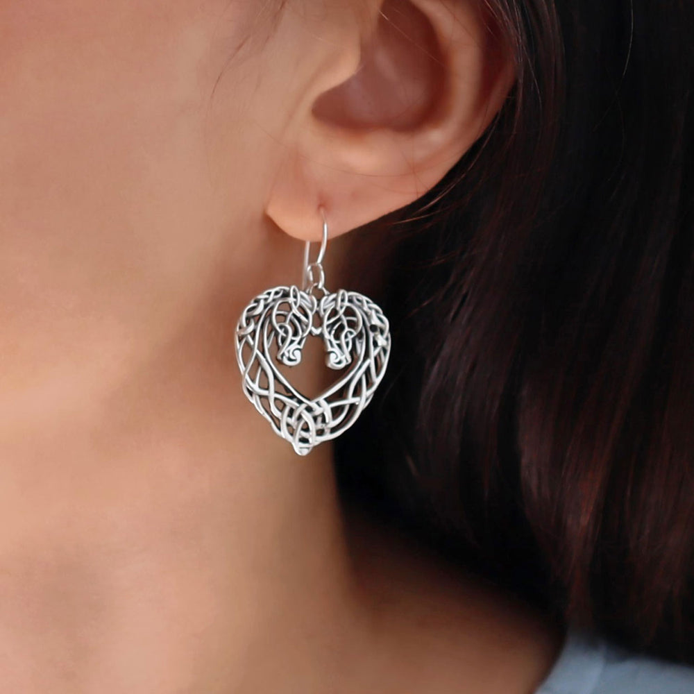 Silver hore head heart-shaped earring worn by a person with dark hair.