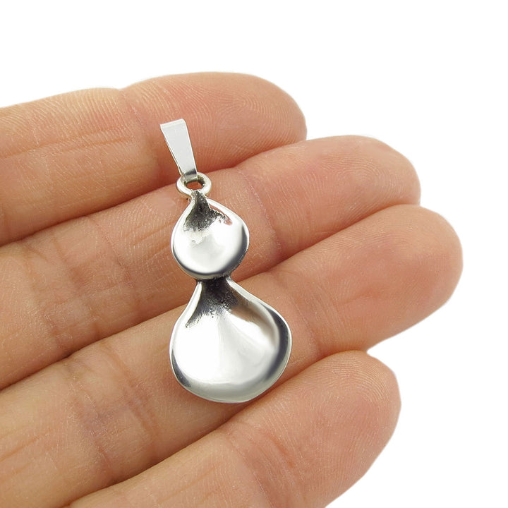 Silver pendant held between fingers on a white background