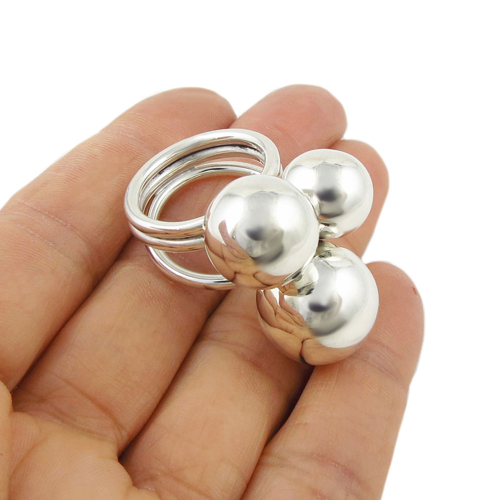 Silver cocktail ring with triple ball beads held in a hand against a white background