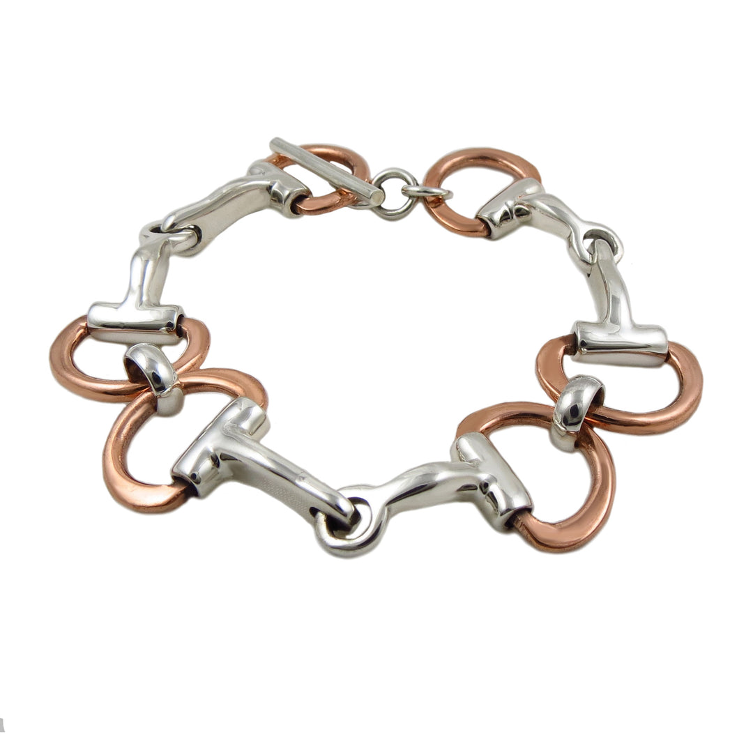 A two-tone horsebit bracelet made of sterling silver with copper-colored rings and a silver-colored eggbutt, fastened with a t-bar toggle.