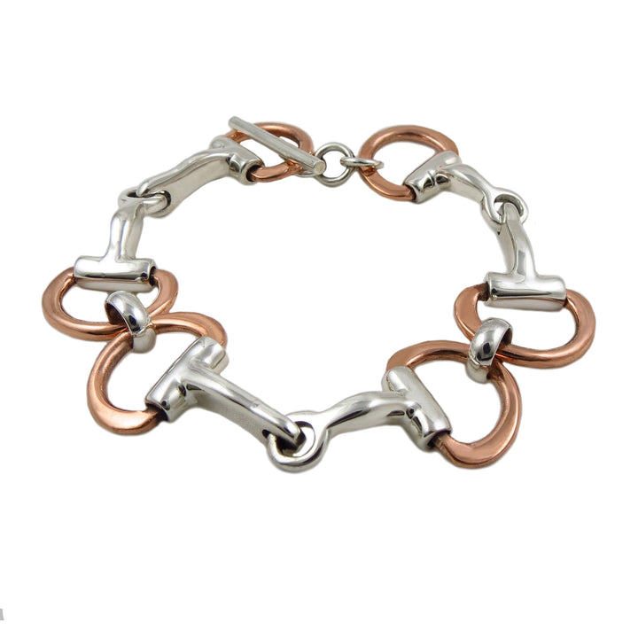 A two-tone horsebit bracelet made of sterling silver with copper-colored rings and a silver-colored eggbutt, fastened with a t-bar toggle.