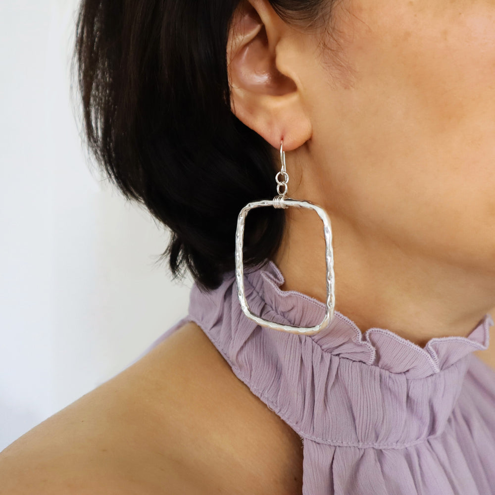 Hammered 925 silver square hoop earrings worn by a woman with a purple blouse