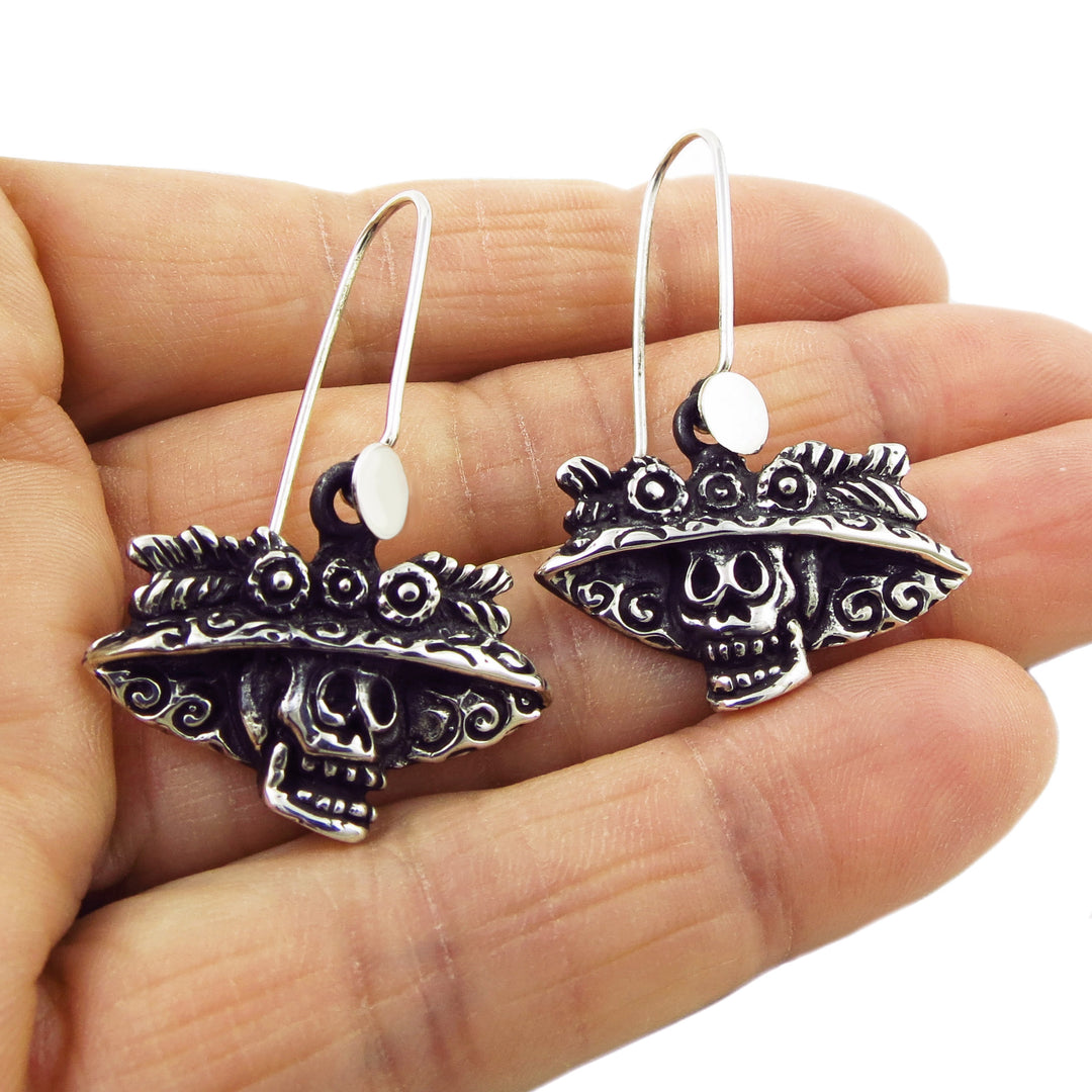 A pair of sterling silver earrings featuring a Day of the Dead Catrina skull design, with blackened and polished finish.