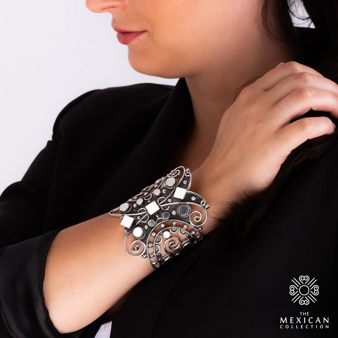 A large statement bracelet cuff in polished and blackened antique sterling silver worn by a woman with a black blouse.