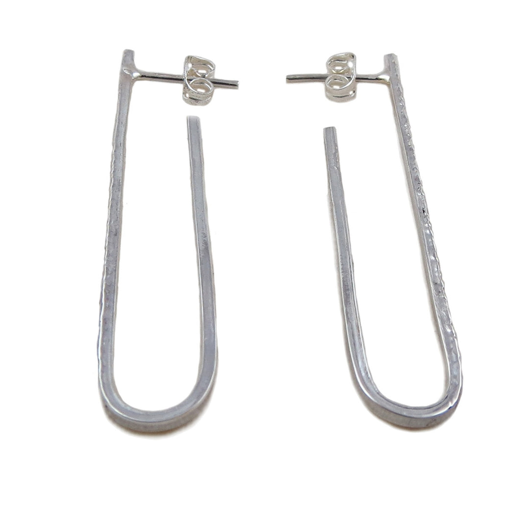 A pair of long drop sterling silver earrings with a textured hammered finish, displayed against a white background.