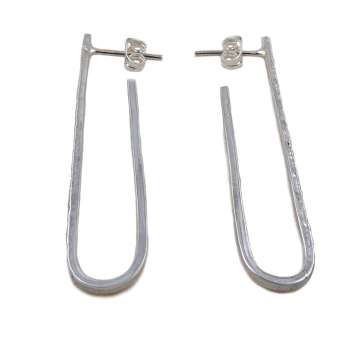 A pair of long drop sterling silver earrings with a textured hammered finish, displayed against a white background.