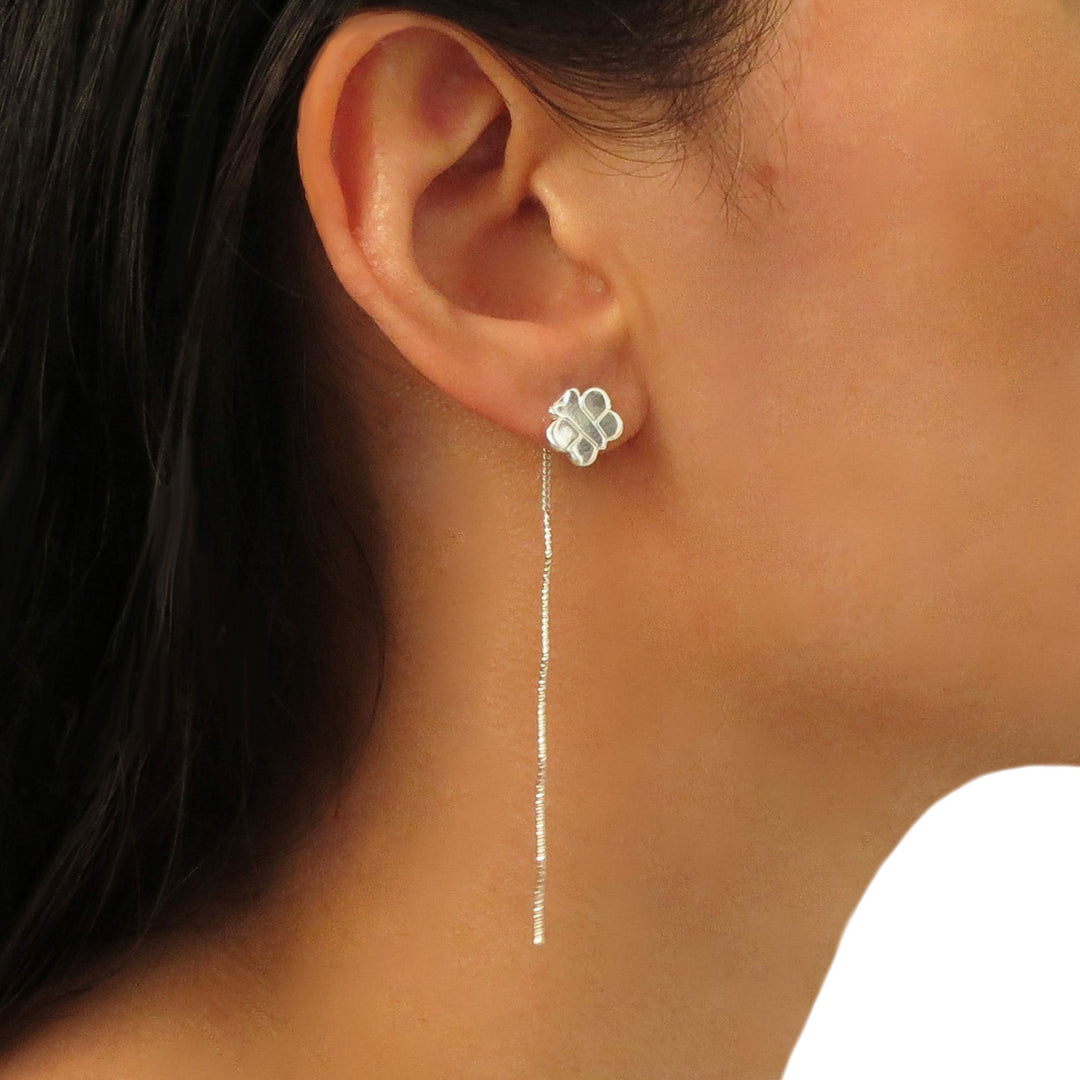 A close-up image of a woman wearing a silver butterfly-shaped drop pull through earring.