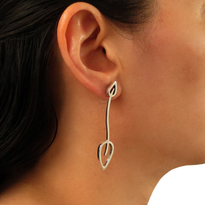 A long sterling silver double leaf design earrings worn by a person