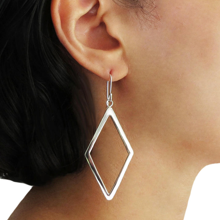 Long diamond-shaped silver earrings being worn by a woman