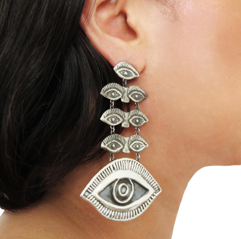 A woman wearing a pair of Mexican designer sterling silver magic eye chandelier earrings.