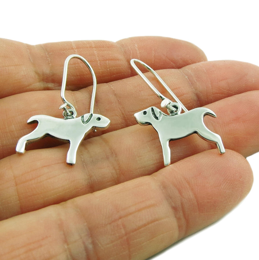 Dog shaped 925 silver earrings held in a person's hand on a white background