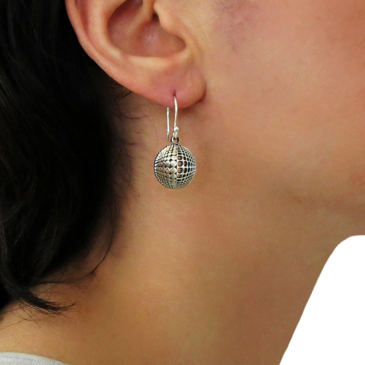 Silver circle earrings with an llusion pattern worn by a woman on a white background