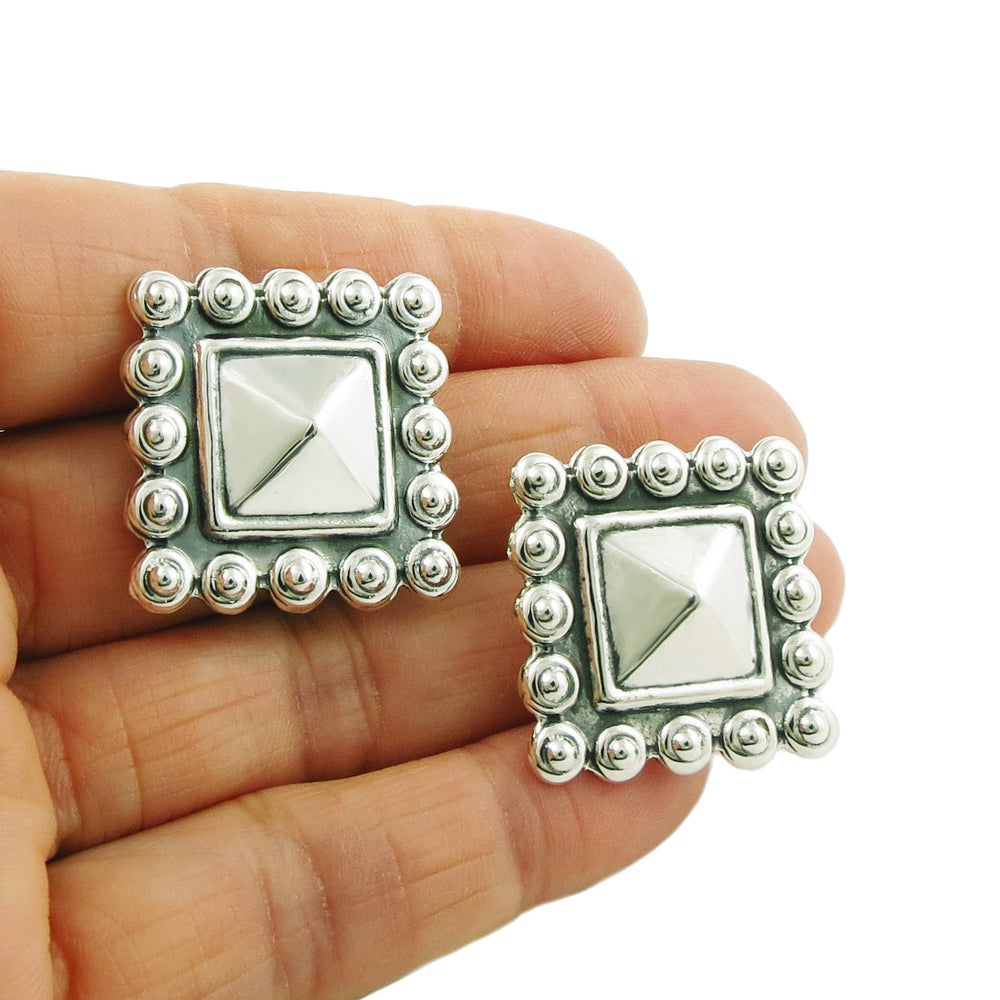 Maria Belen Nilson designer square stud earring in 925 silver held in a person's hand.
